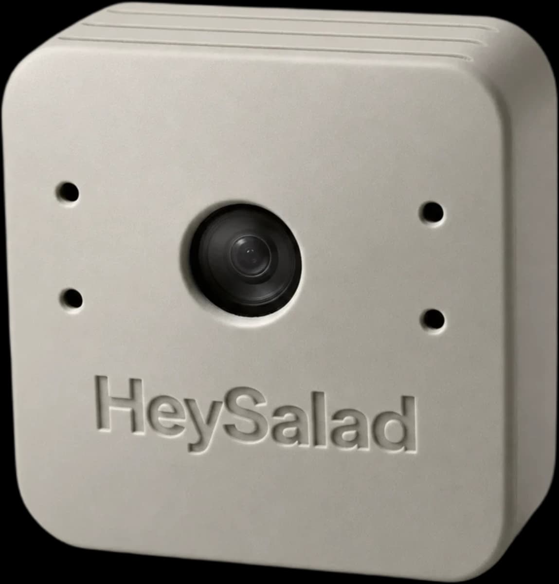 The HeySalad AI Camera: a matte grey square housing with radiused corners, a central dark lens, four small front-face openings and the HeySalad wordmark debossed below.